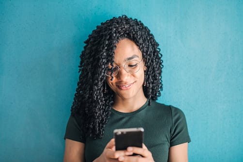 portrait photo of smiling woman in black t shirt and glasses using her smartphone