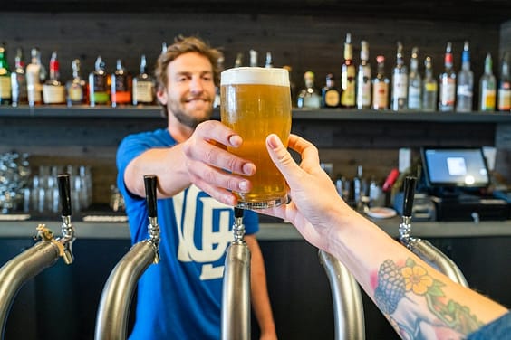 man handing a person a glass of beer