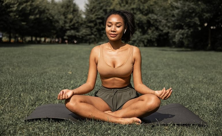 fit ethnic woman practicing yoga in park