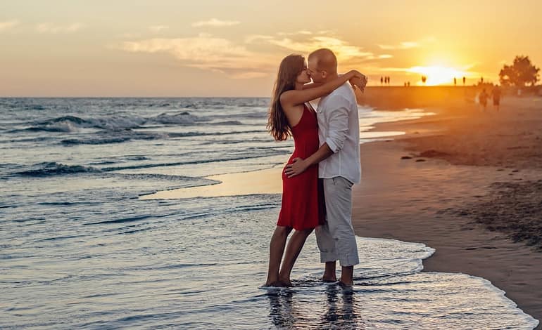 couple kissing on beach during golden hour
