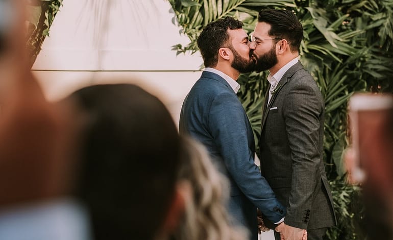men wearing suit kissing in front of people