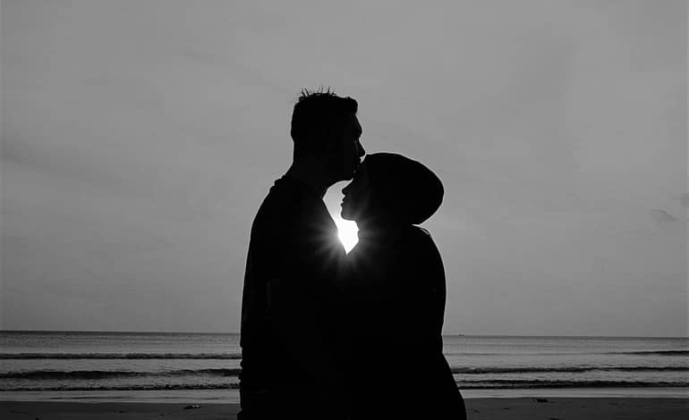 silhouette of man and woman standing on beach