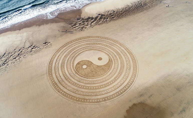 yin yang symbol on brown beach sand