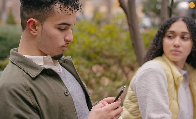 hispanic lady looking jealously at boyfriend while texting on cellphone